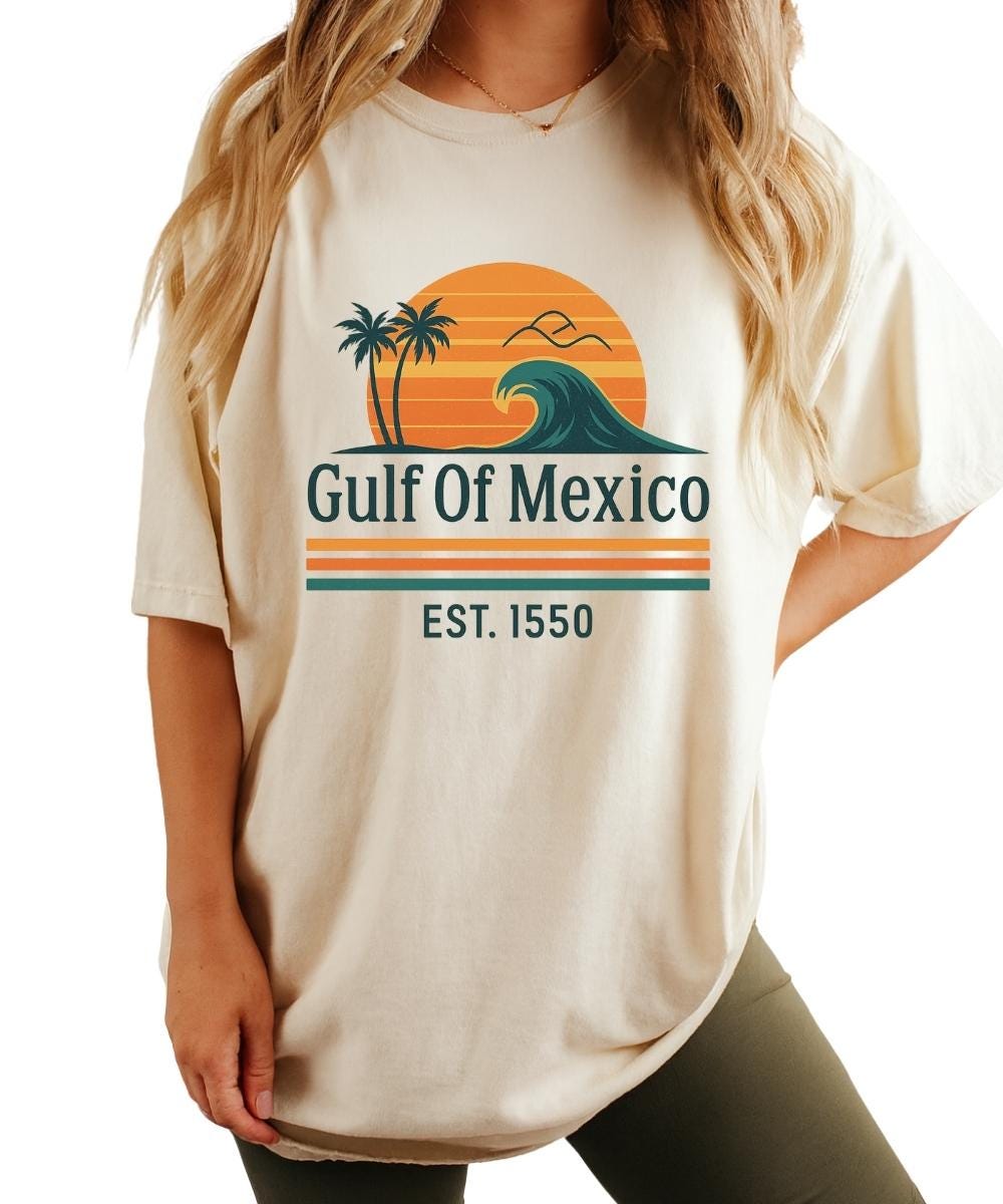 Gulf of Mexico shirt with retro sunset, wave and palm trees graphic and text “Est. 1550” on a light tan t-shirt